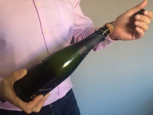 Abrir una botella de champagne o cava. Imagen. La mano Izquierda la deslizamos hacia arriba y procedemos a quitar el capuchón. Abrir una botella de champagne o cava.